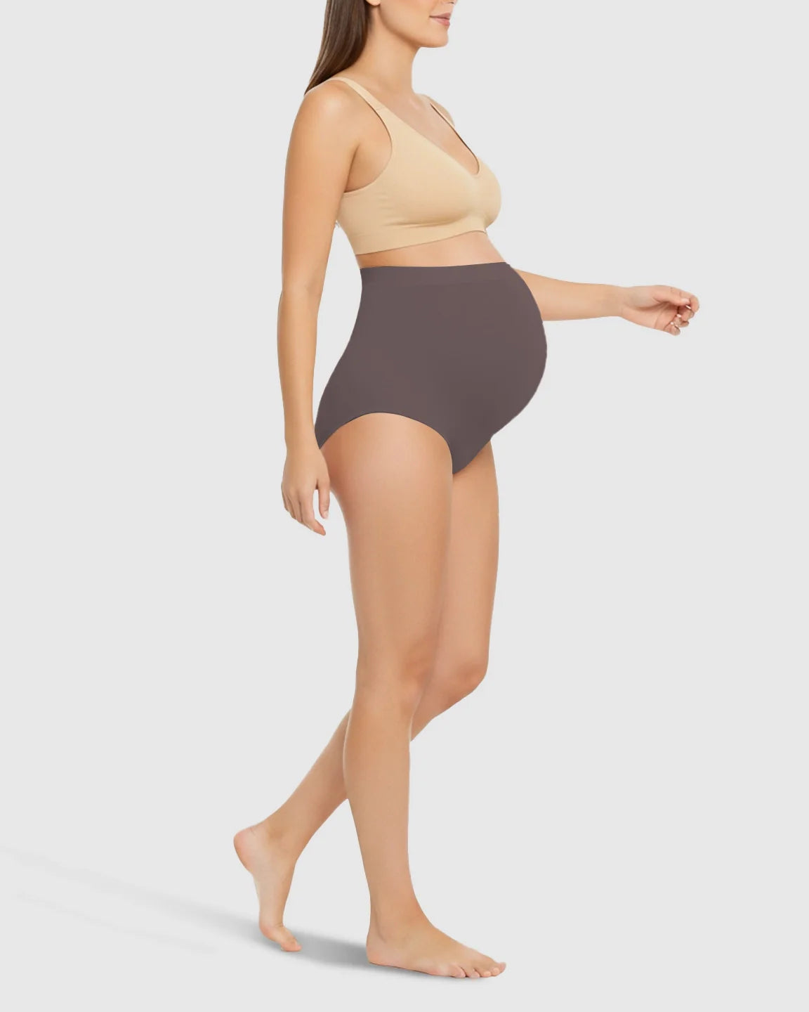 Maternity model wearing Bump Society high-waist seamless belly-support underwear in dark grey with a beige bra.