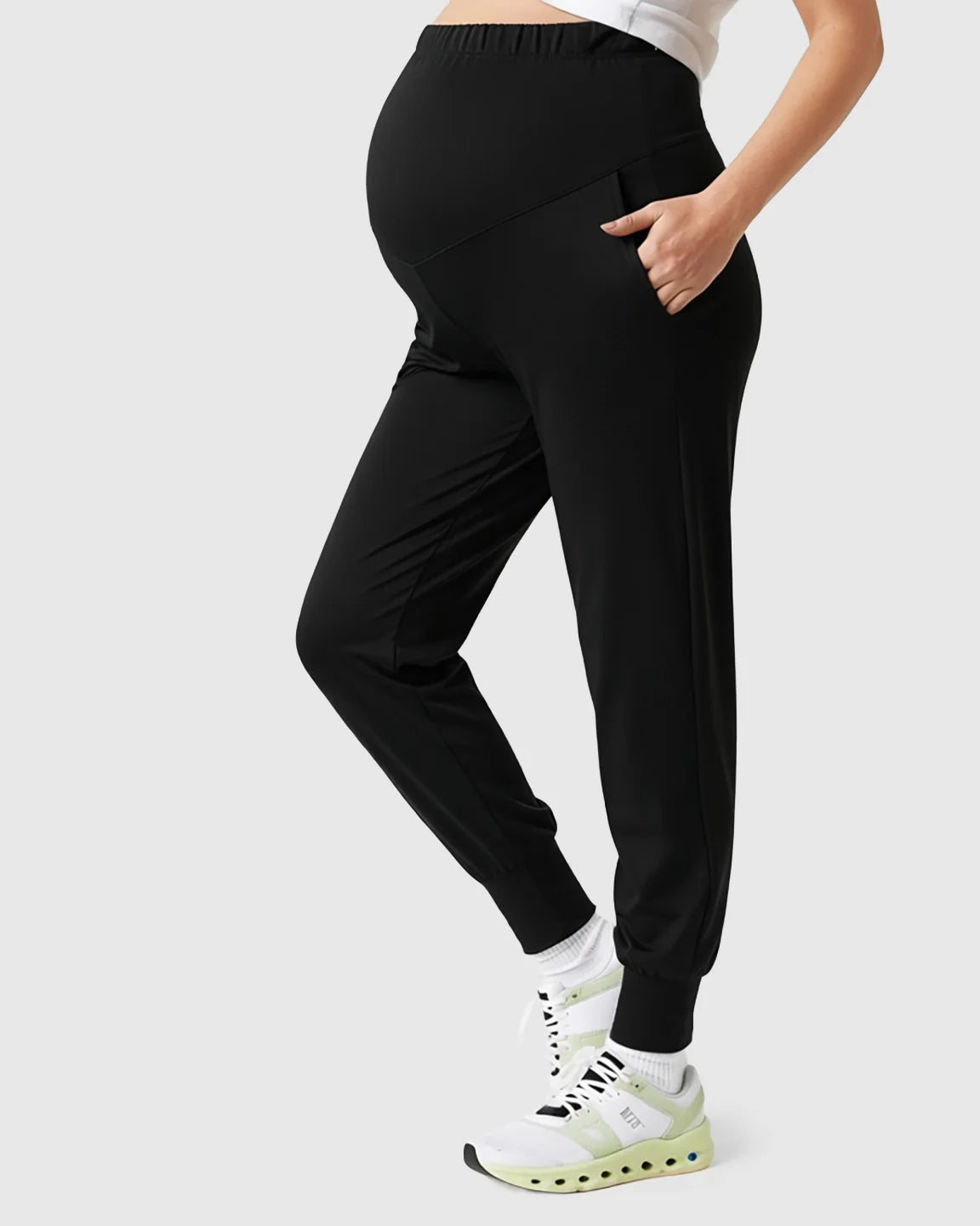 Black supportive slim-fitting maternity joggers with a high-waist design and pockets, worn by a pregnant model.