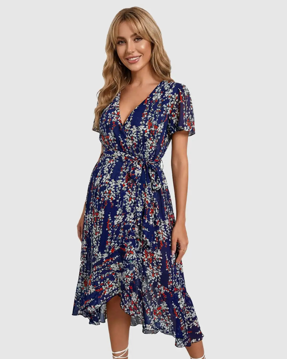 Smiling pregnant woman in a blue floral V-neck ruffled hem maternity midi dress.