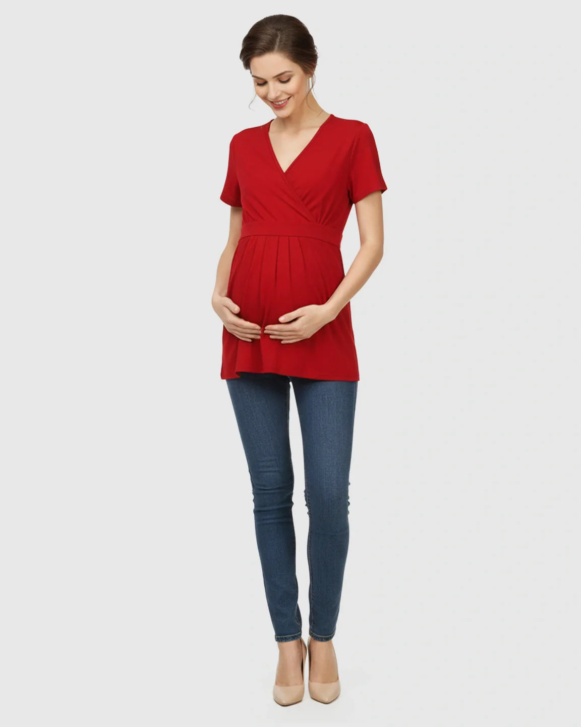 Pregnant woman in a red V-neck wrap-style maternity top with an adjustable waist tie, paired with jeans.