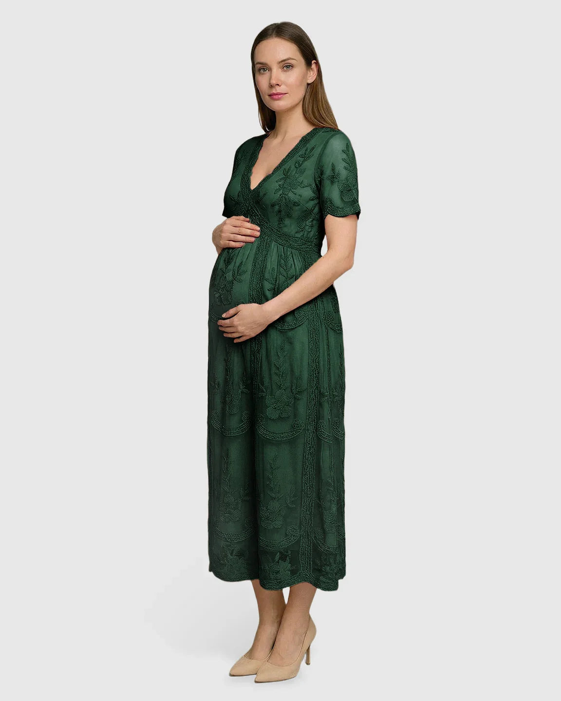 Pregnant woman in a dark green lace maternity midi dress with V-neck, short sleeves, and intricate embroidery.
