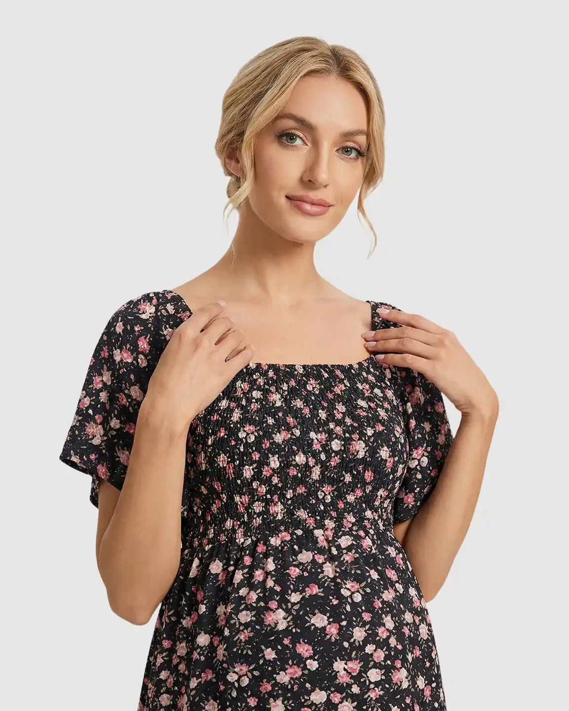 Black floral flutter-sleeve smocked maternity midi dress with pink flowers.