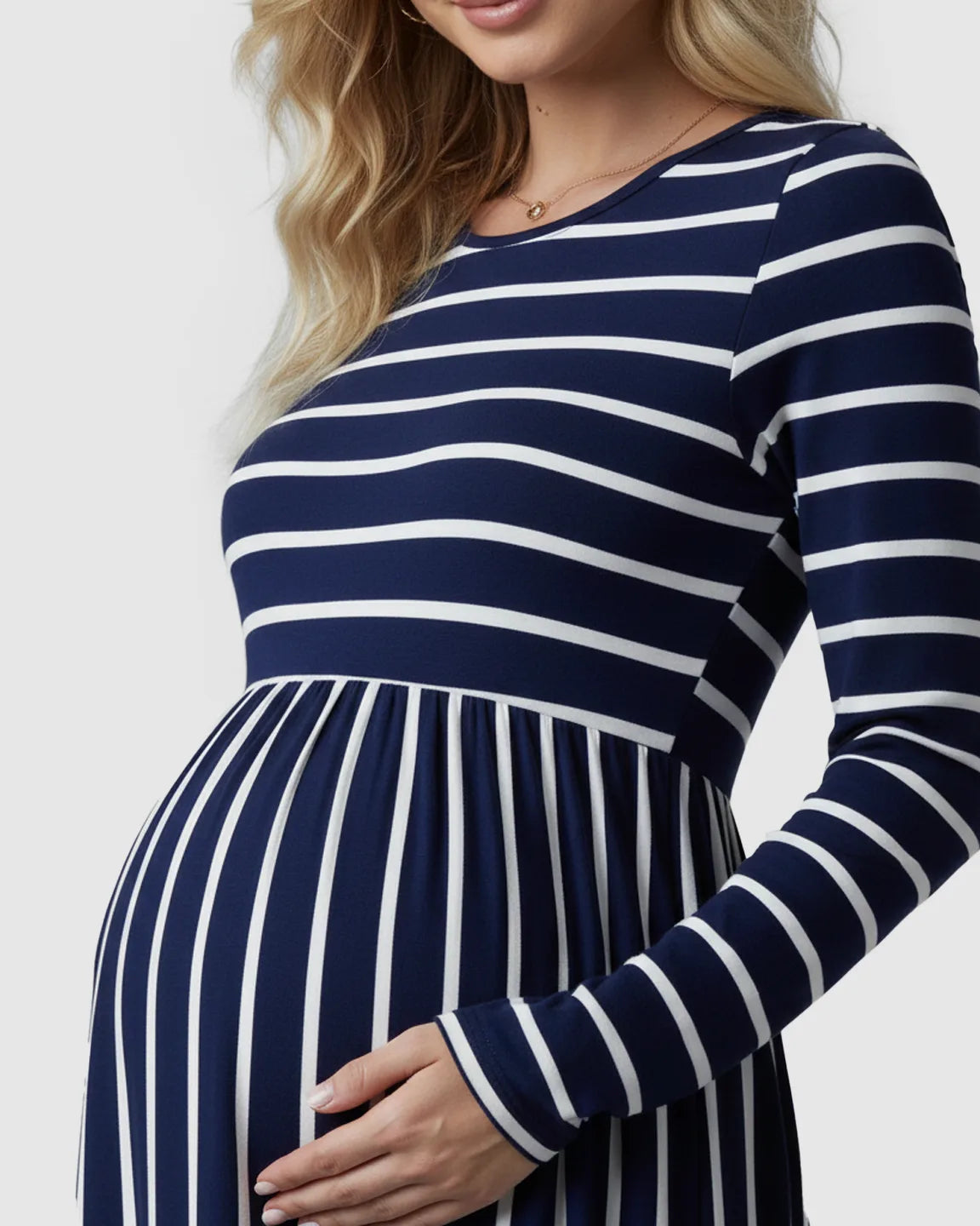 Pregnant woman in a navy and white striped long sleeve maternity maxi dress, holding her baby bump.