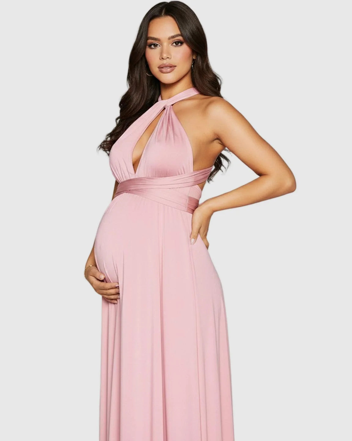 Pregnant woman in a pink tie-waist flowy maternity maxi dress with a halter neckline.
