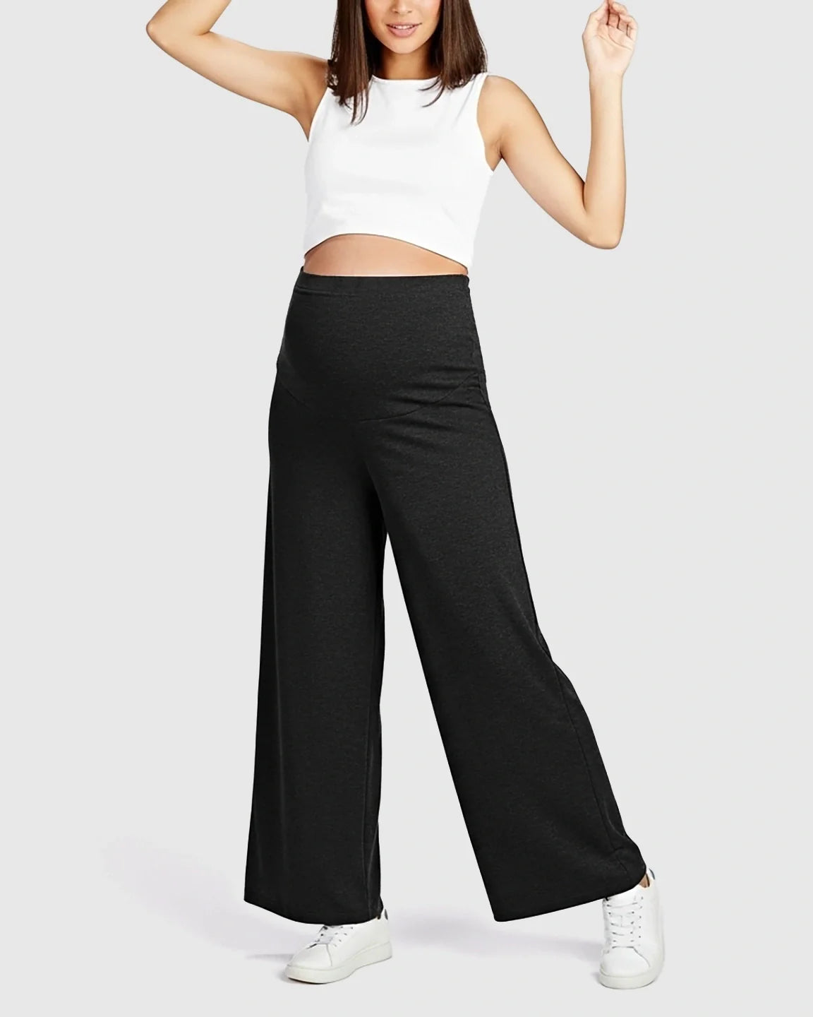 Woman wearing charcoal grey Comfort Fit elastic waist maternity pants with a white crop top.