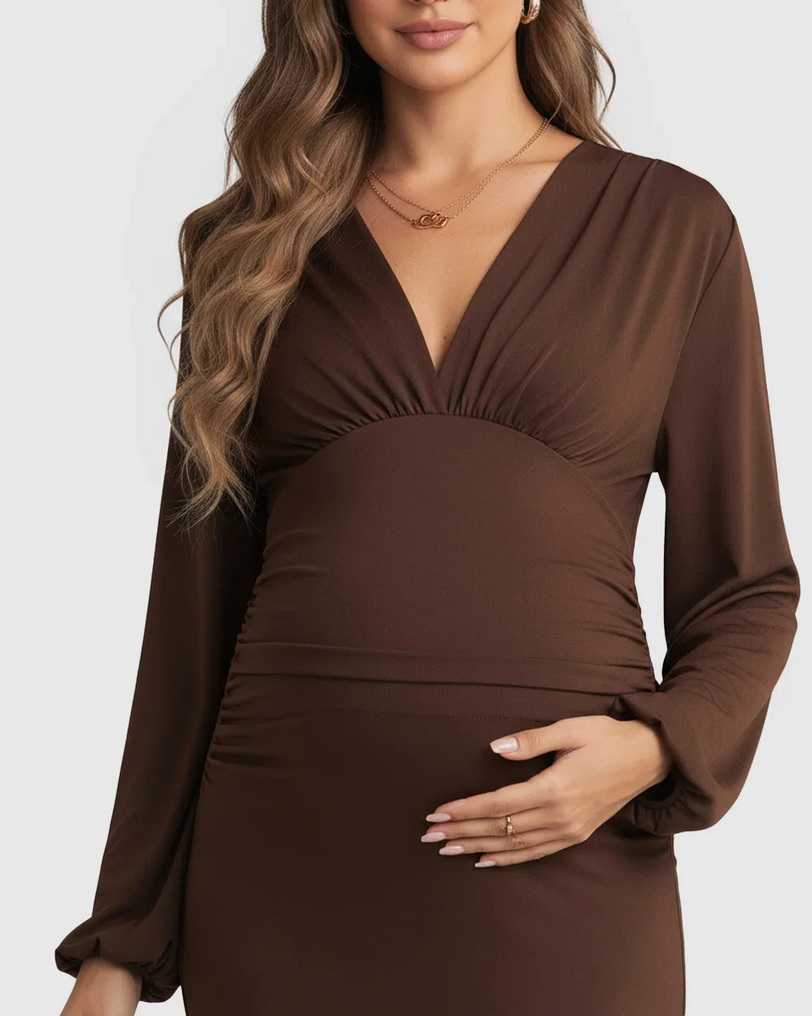 Pregnant woman in a brown long-sleeve bodycon maternity maxi dress with a deep V-neckline.