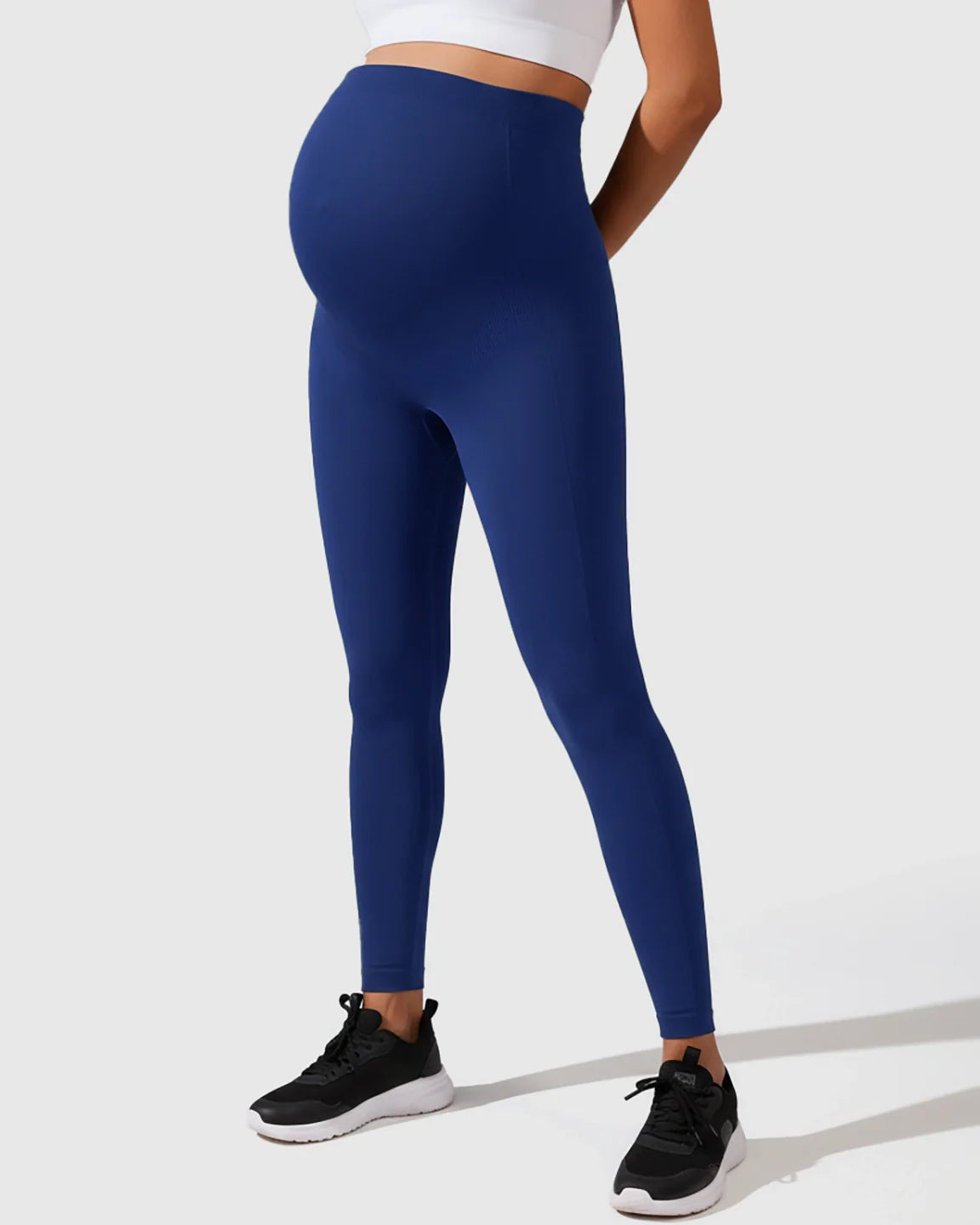 Seamless M-shape maternity leggings in deep blue, high-waisted for full belly support, worn by a pregnant model.