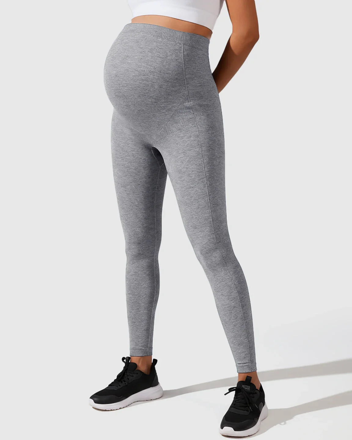Gray seamless M-shape maternity leggings with full-belly support, worn by a pregnant woman.