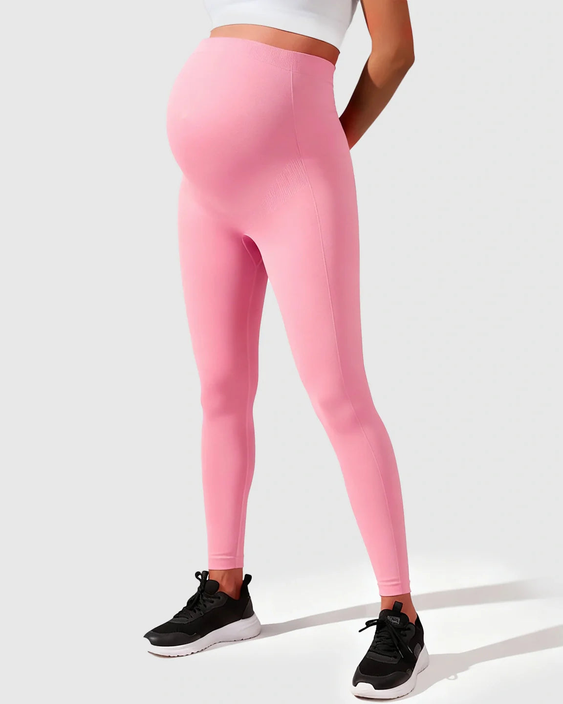 Pink seamless M-shape maternity leggings on a pregnant model, featuring a high-waisted, full-belly support design.