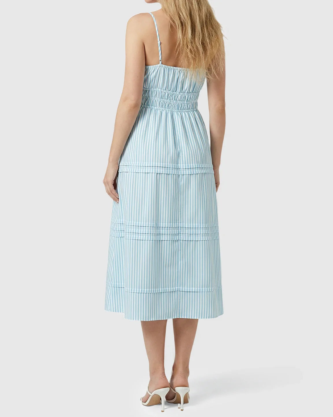 Back view of a blonde woman in a blue and white striped smocked-waist maternity midi dress with spaghetti straps.