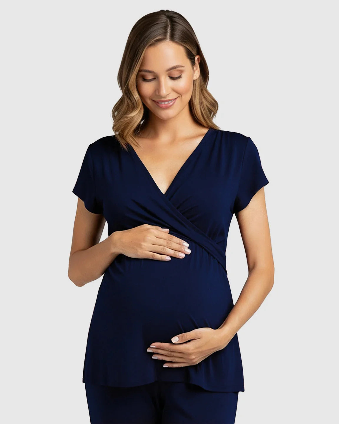 Smiling pregnant woman in a navy wrap V-neck short-sleeve maternity and nursing top.
