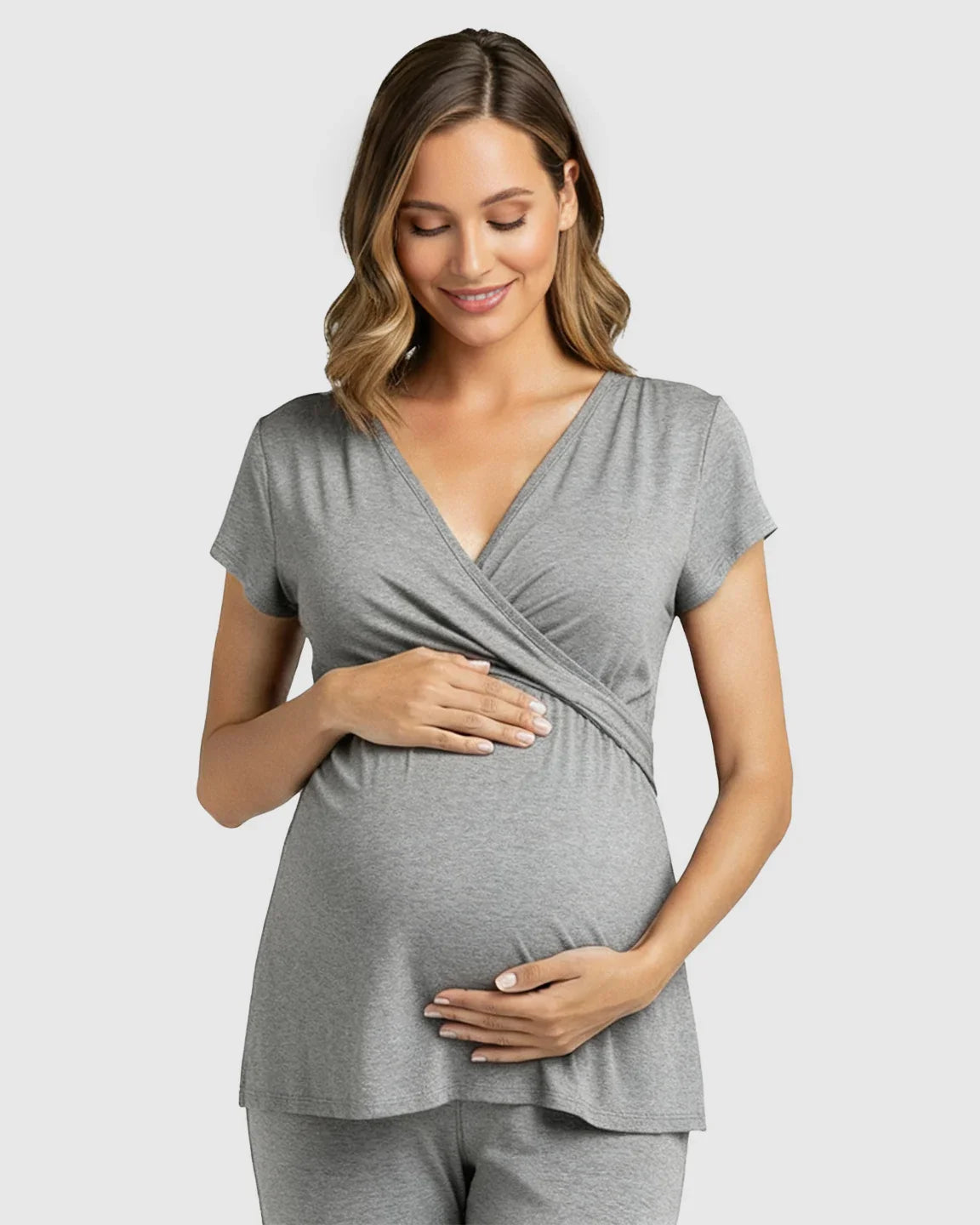 Smiling pregnant woman in a soft gray wrap V-neck short-sleeve maternity and nursing top.