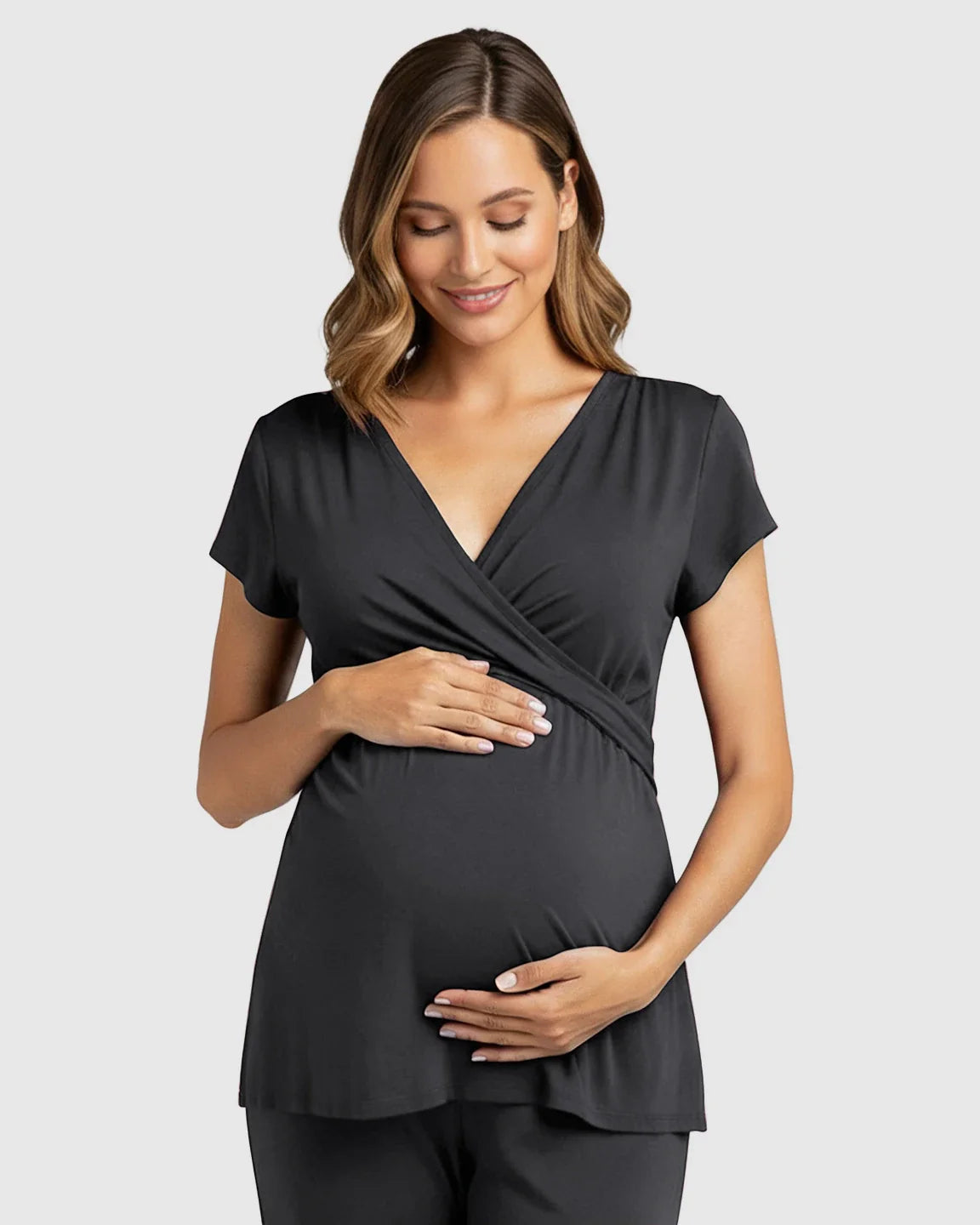 Smiling pregnant woman in a black wrap V-neck short-sleeve maternity and nursing top.