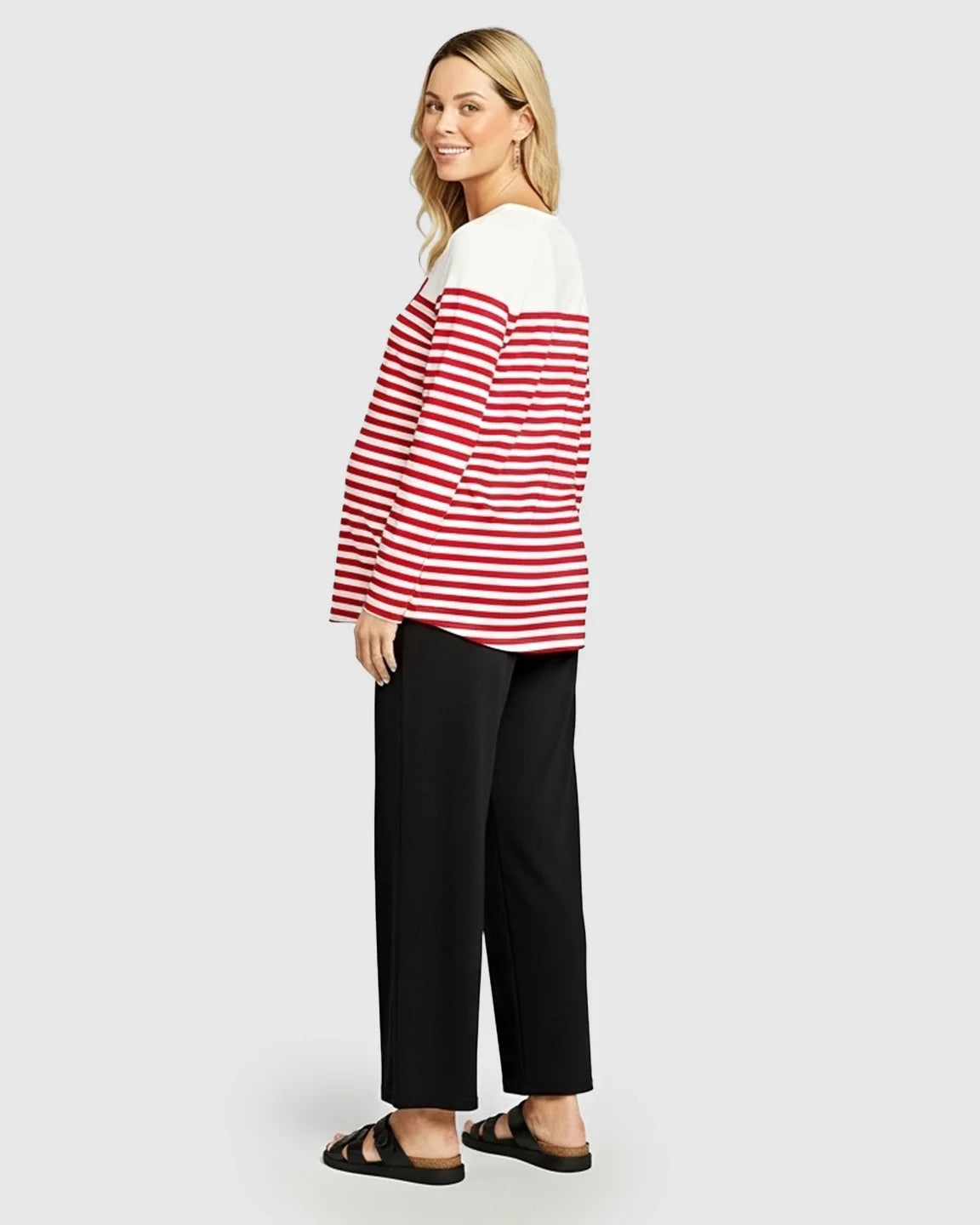 Smiling pregnant woman in a red and white striped loose-fit long-sleeve maternity top.