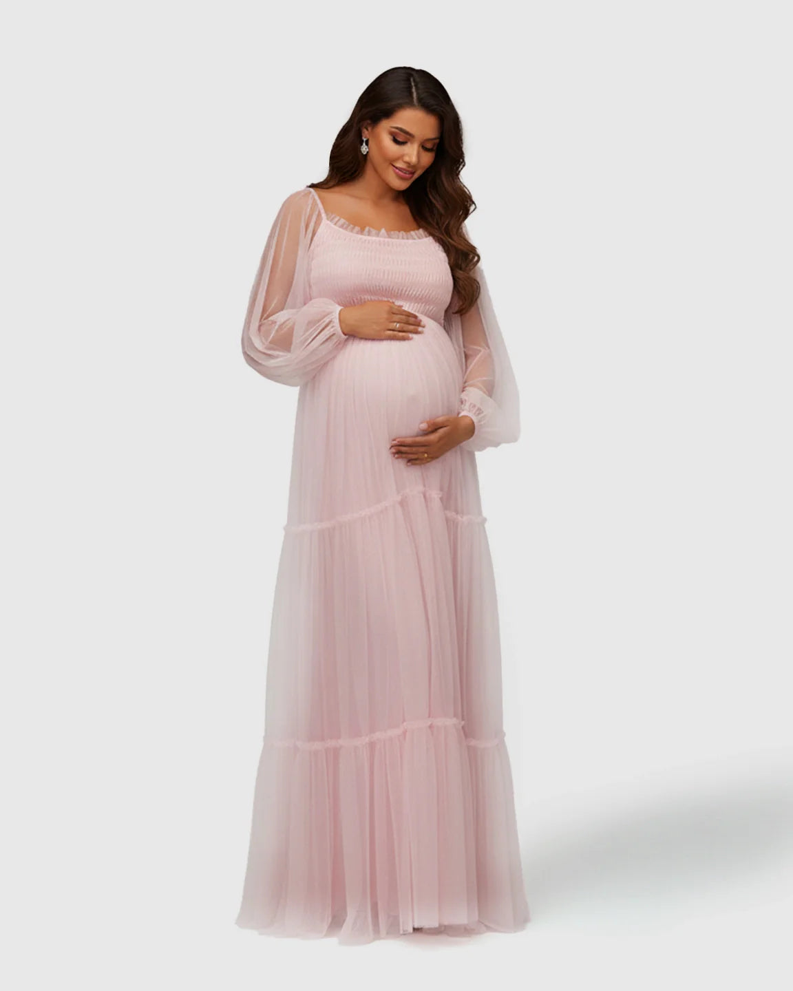 Maternity model in a pink tiered tulle maxi gown with lantern sleeves and smocked bodice.