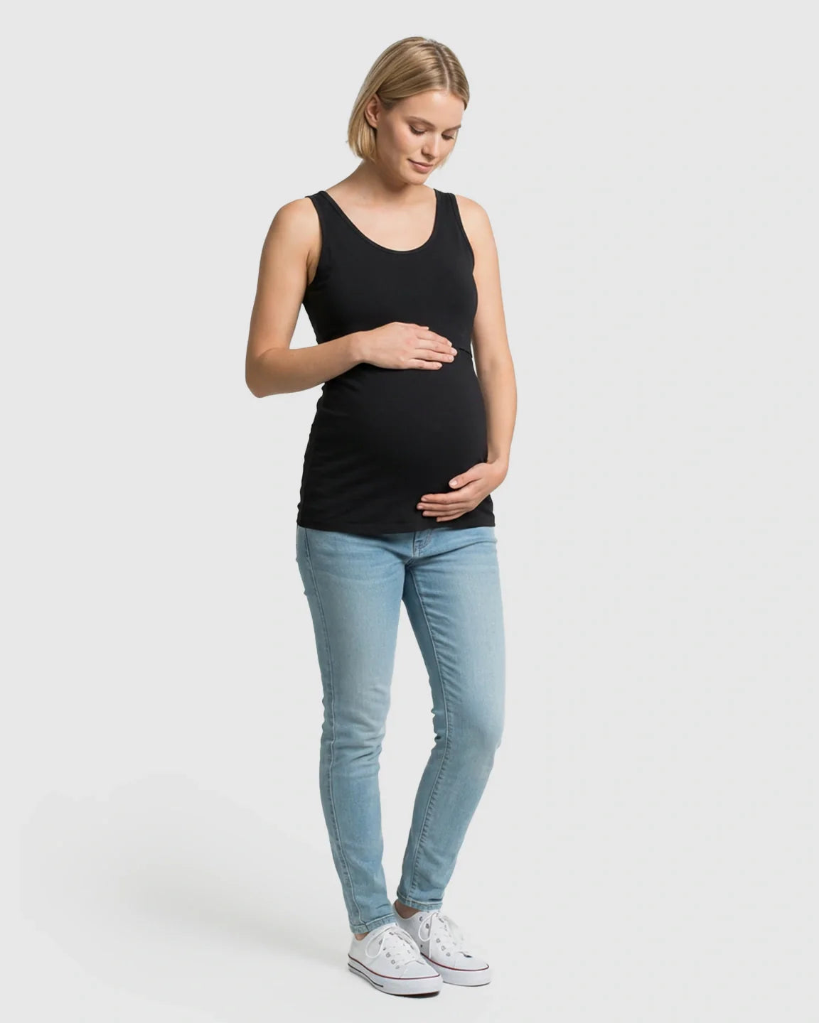 Pregnant woman in a black stretch nursing-access maternity tank top and light wash jeans.