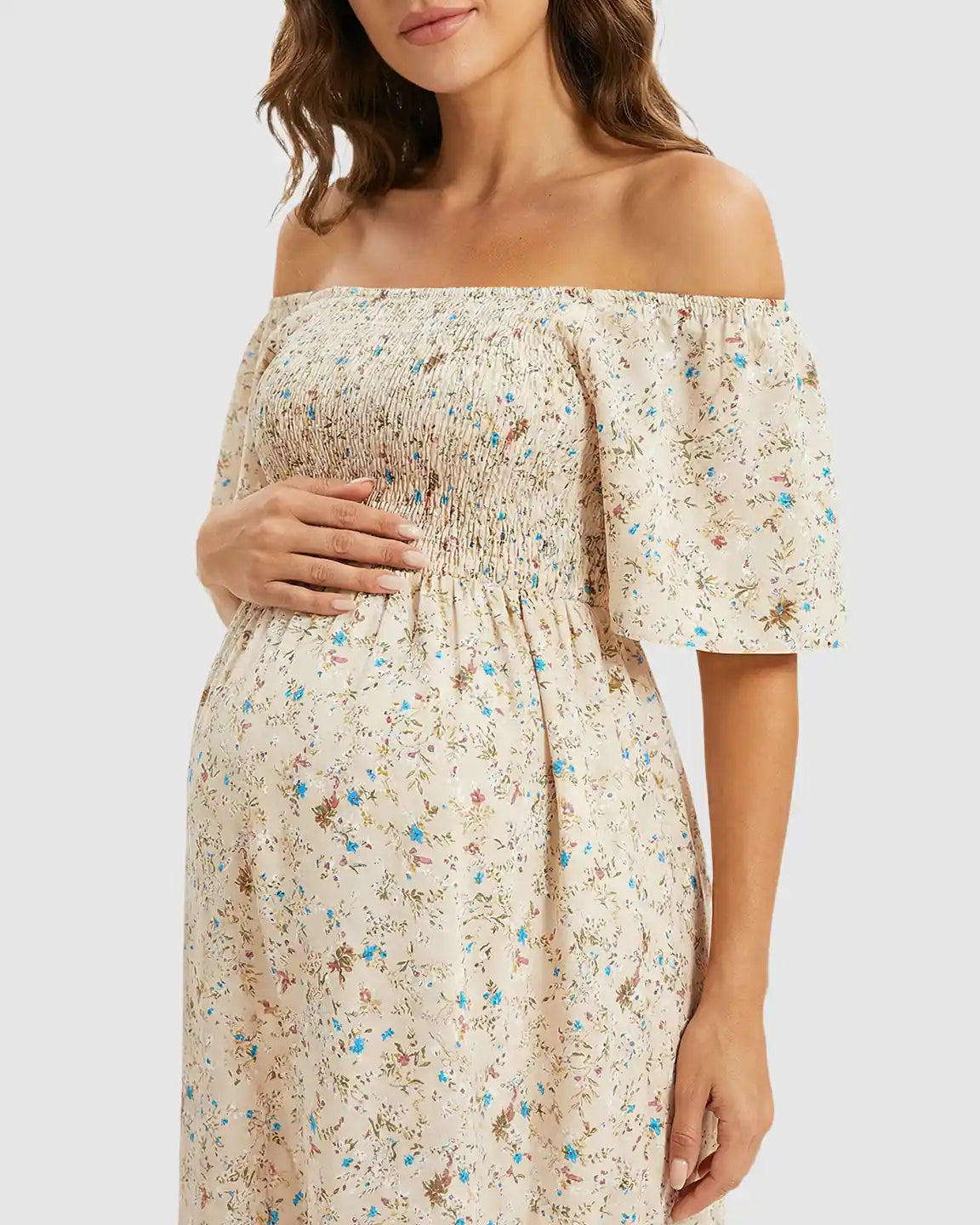 Maternity midi dress with off-shoulder smocked top, flutter sleeves, and a tiered floral skirt.