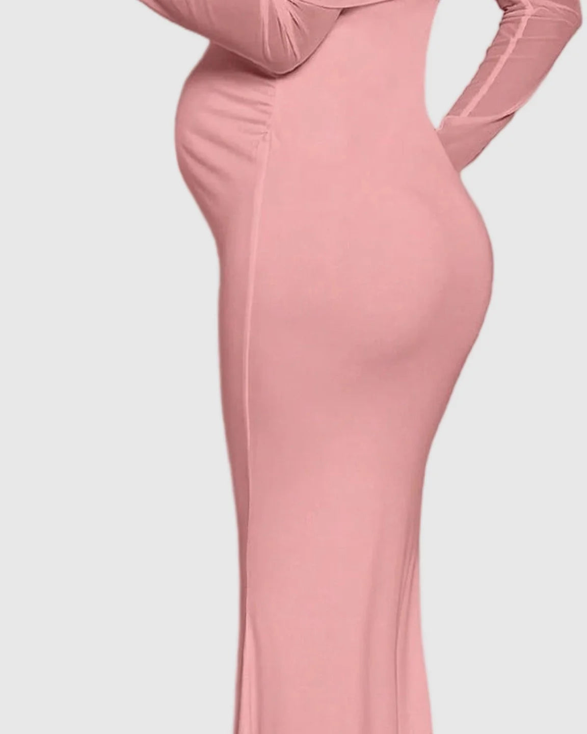Pink draped neck mermaid fit maternity maxi dress, off-shoulder with sheer long sleeves, highlighting a pregnant belly.