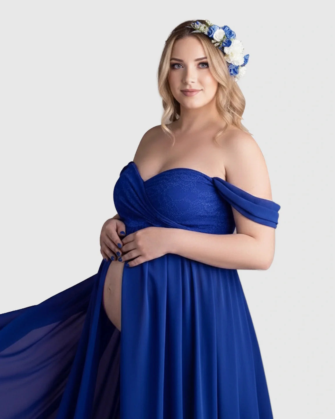 Pregnant woman in a royal blue off-shoulder chiffon maternity gown with a long train, wearing a floral crown.
