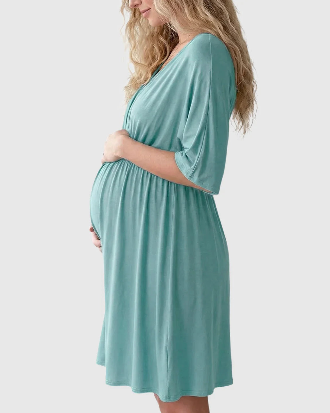 Pregnant woman in a teal cross-front maternity midi dress with 3/4 sleeves, flattering her bump.