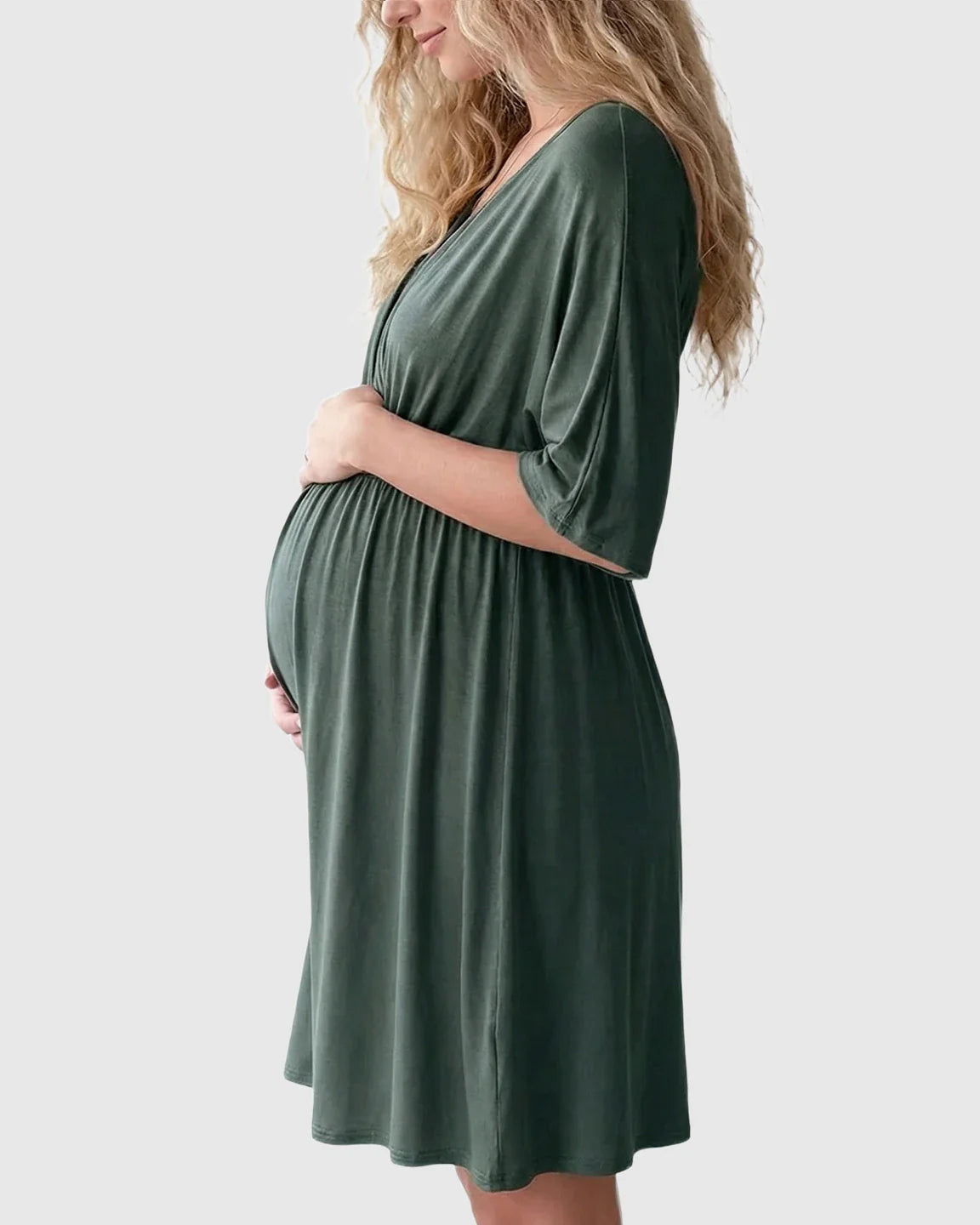 Pregnant woman in a dark green cross-front maternity midi dress with 3/4 sleeves, flattering her bump.