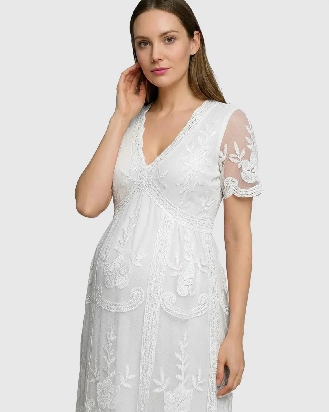 White lace maternity midi dress with V-neck, three-quarter sleeves, and intricate floral embroidery.
