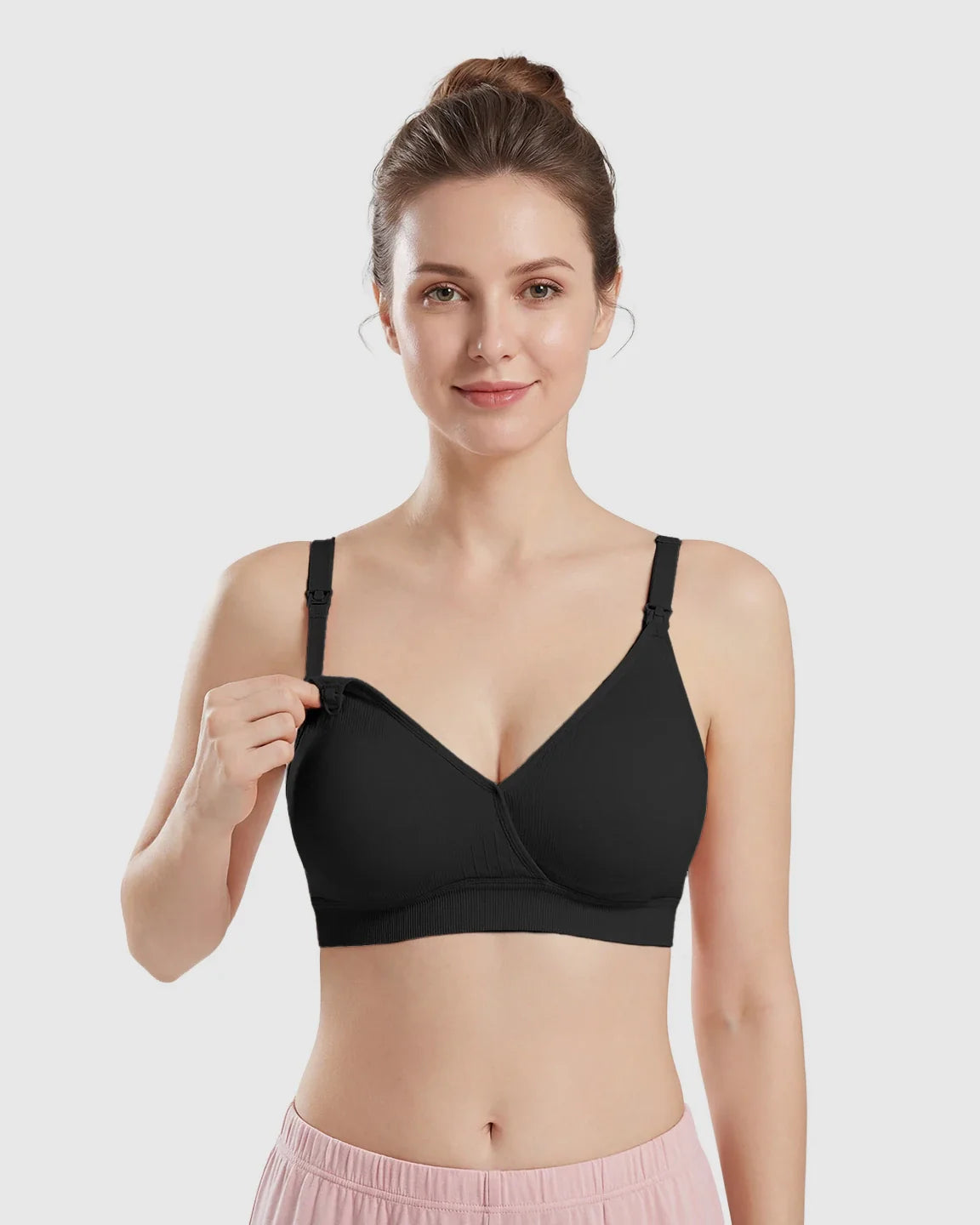 Woman models a black seamless cross-front wireless nursing bra with a drop-down cup for easy access.