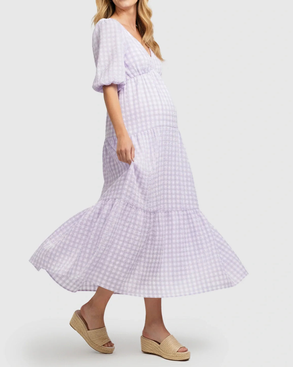 Pregnant woman in a lavender gingham puffed sleeve tiered maxi dress with espadrille sandals.