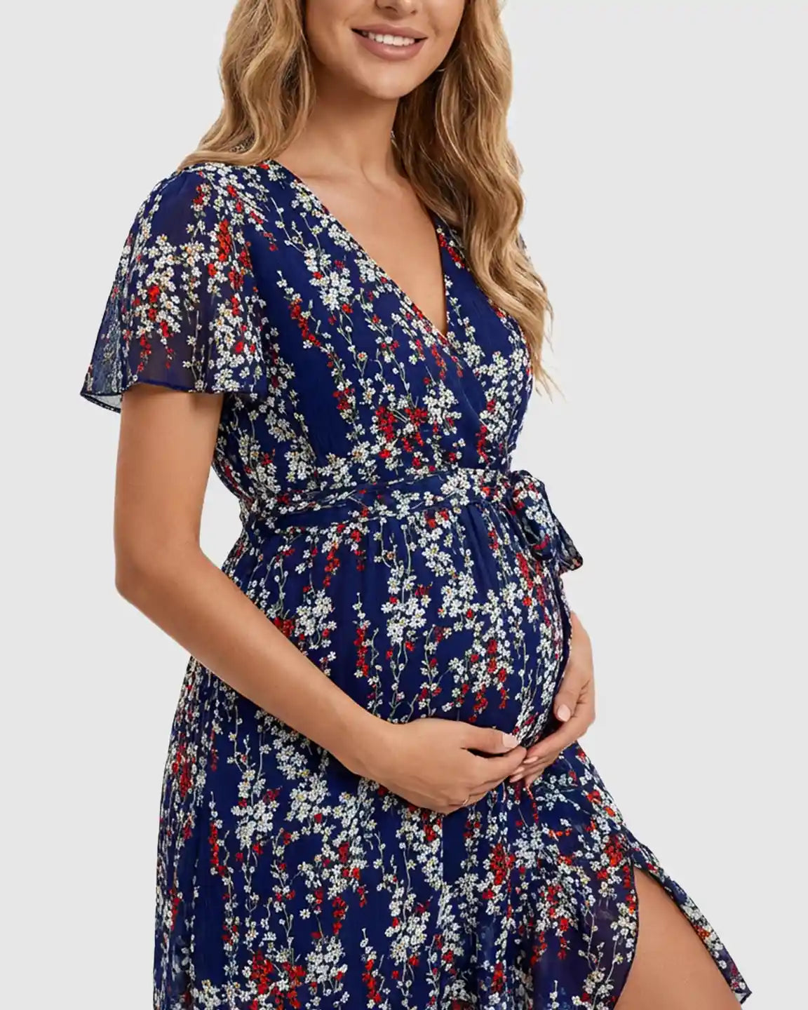 Maternity midi dress in blue floral print with V-neck, flutter sleeves, tie waist, and ruffled hem.