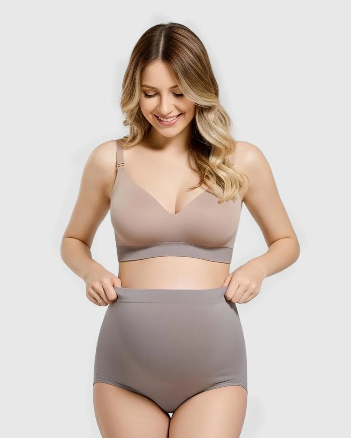 Smiling pregnant woman in a beige bra and gray seamless high-waist maternity panties.