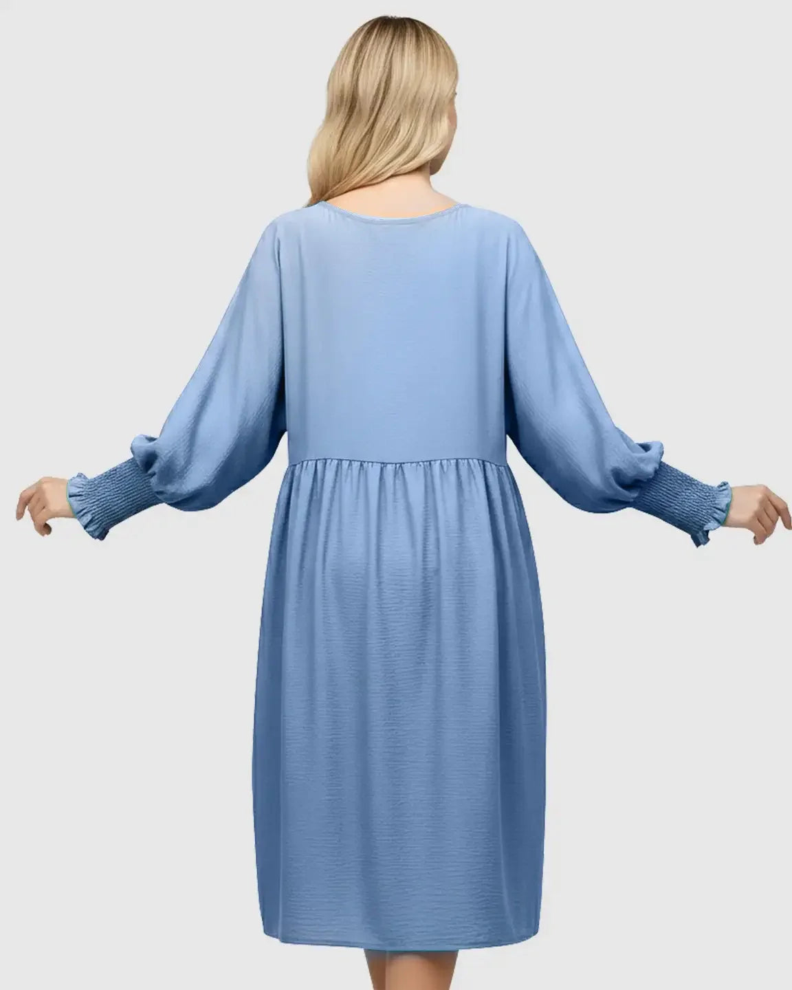 Back view of a blonde woman in a blue smocked sleeve casual maternity dress with a relaxed fit.
