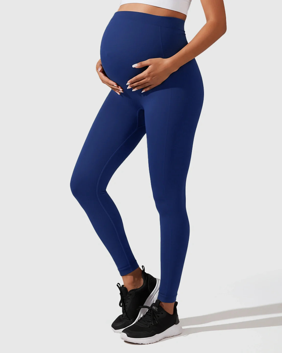 Pregnant woman wearing navy blue seamless M-shape maternity leggings with full-belly support.