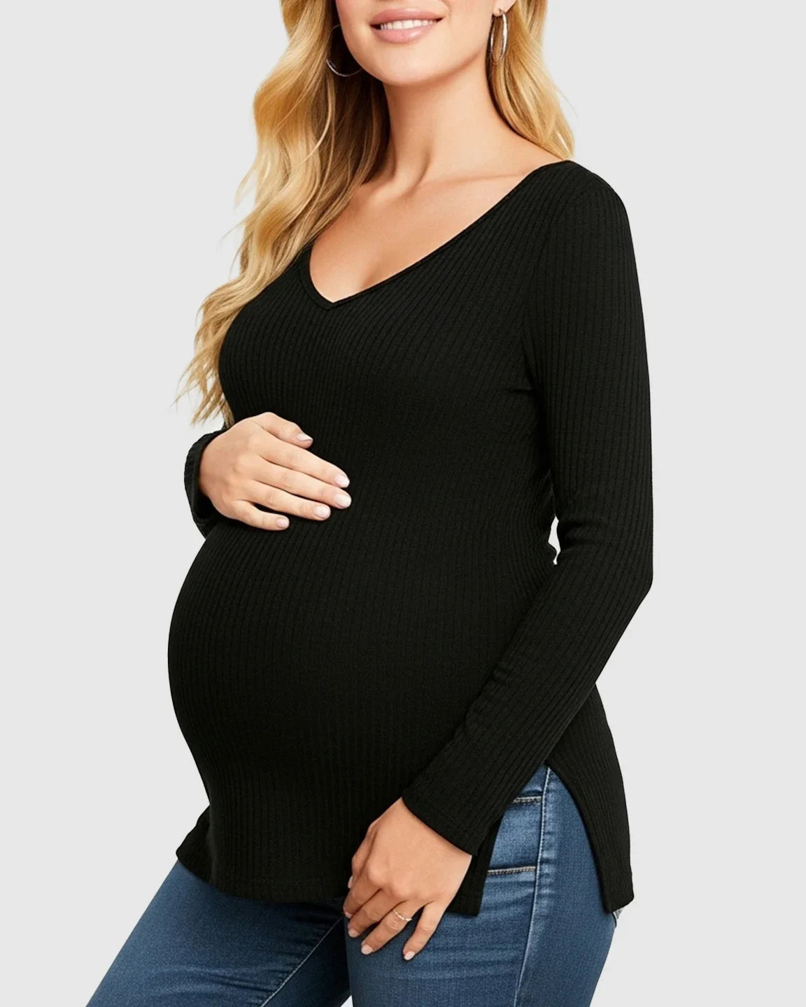 Pregnant woman in a black ribbed V-neck long sleeve maternity top with side slits, paired with jeans.