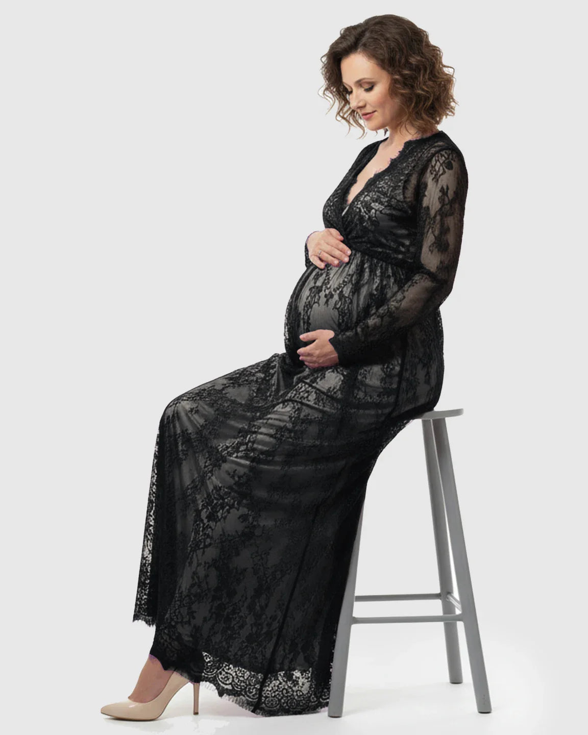 Maternity maxi dress in black sheer floral lace, empire waist, V-neck, long sleeves, worn by a pregnant woman.