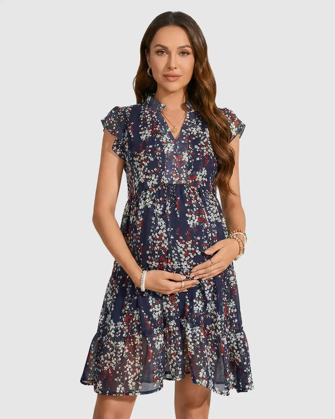 Pregnant woman in a navy floral print chiffon maternity dress with flutter sleeves and an A-line design.