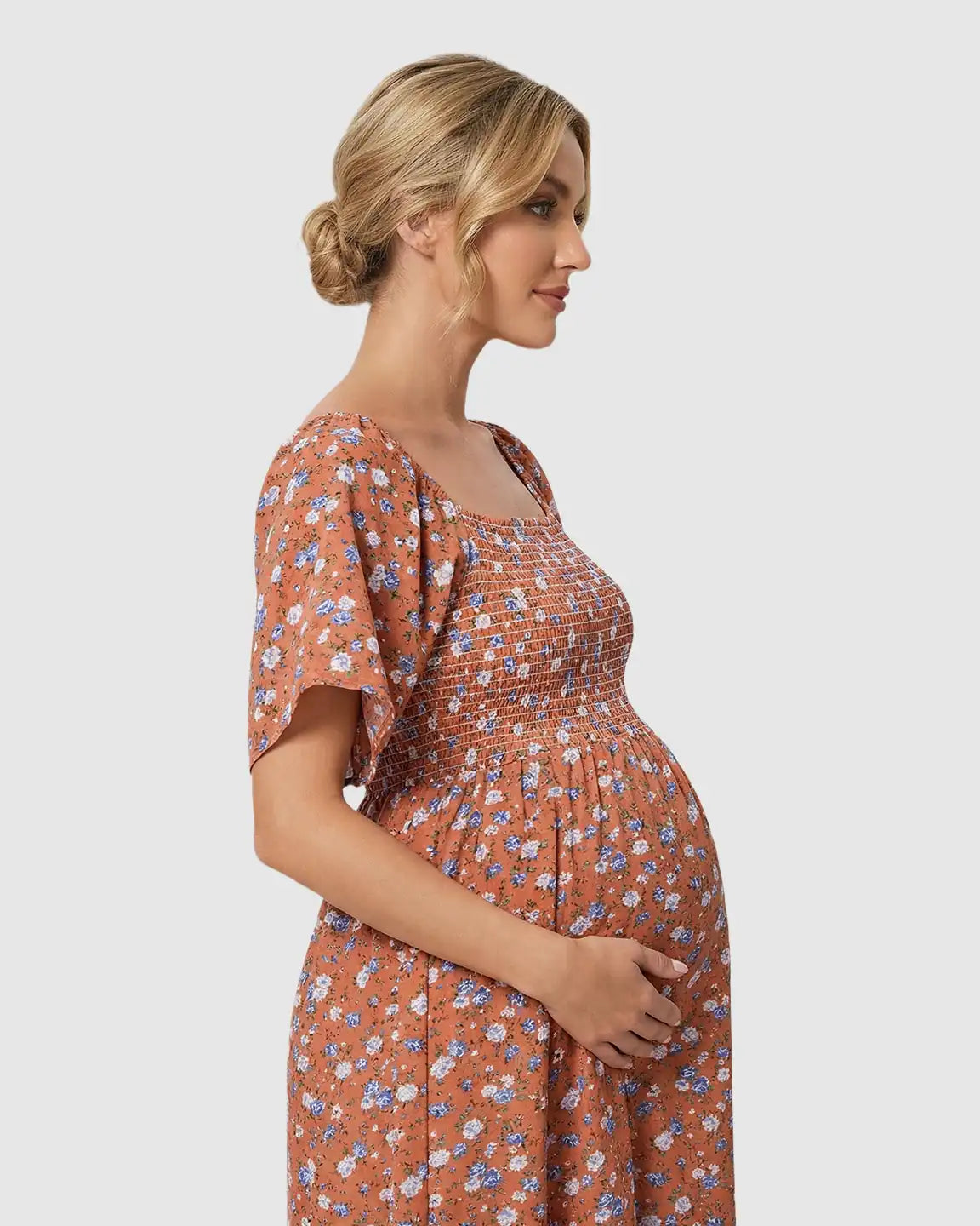 Maternity midi dress in terracotta with blue floral print, flutter sleeves, and smocked bodice.