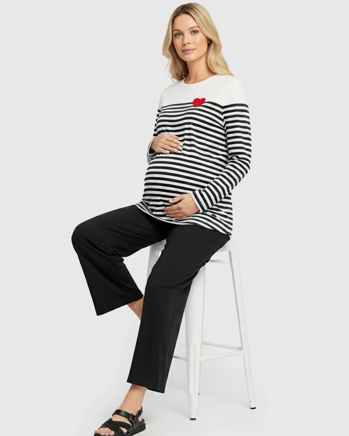 Maternity model in black-white striped long-sleeve top with red heart embroidery and black pants.