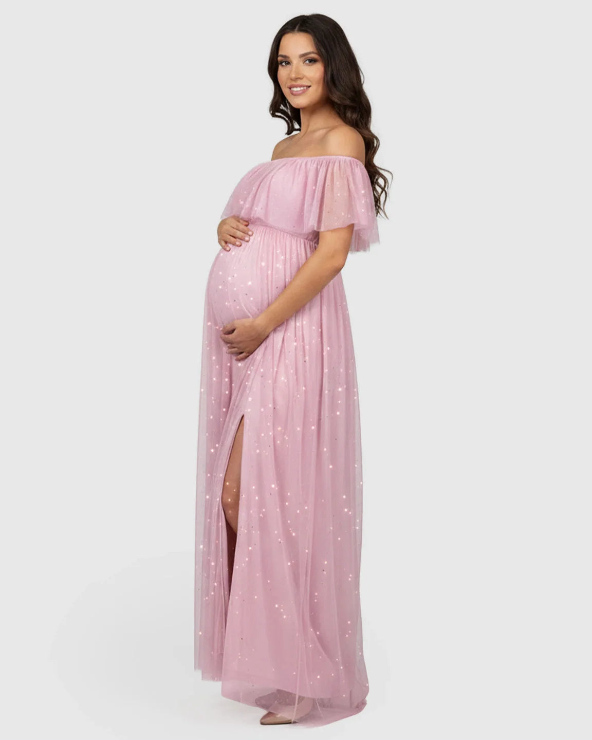Smiling pregnant woman in a pink off-shoulder mesh slit maternity gown with glitter details.