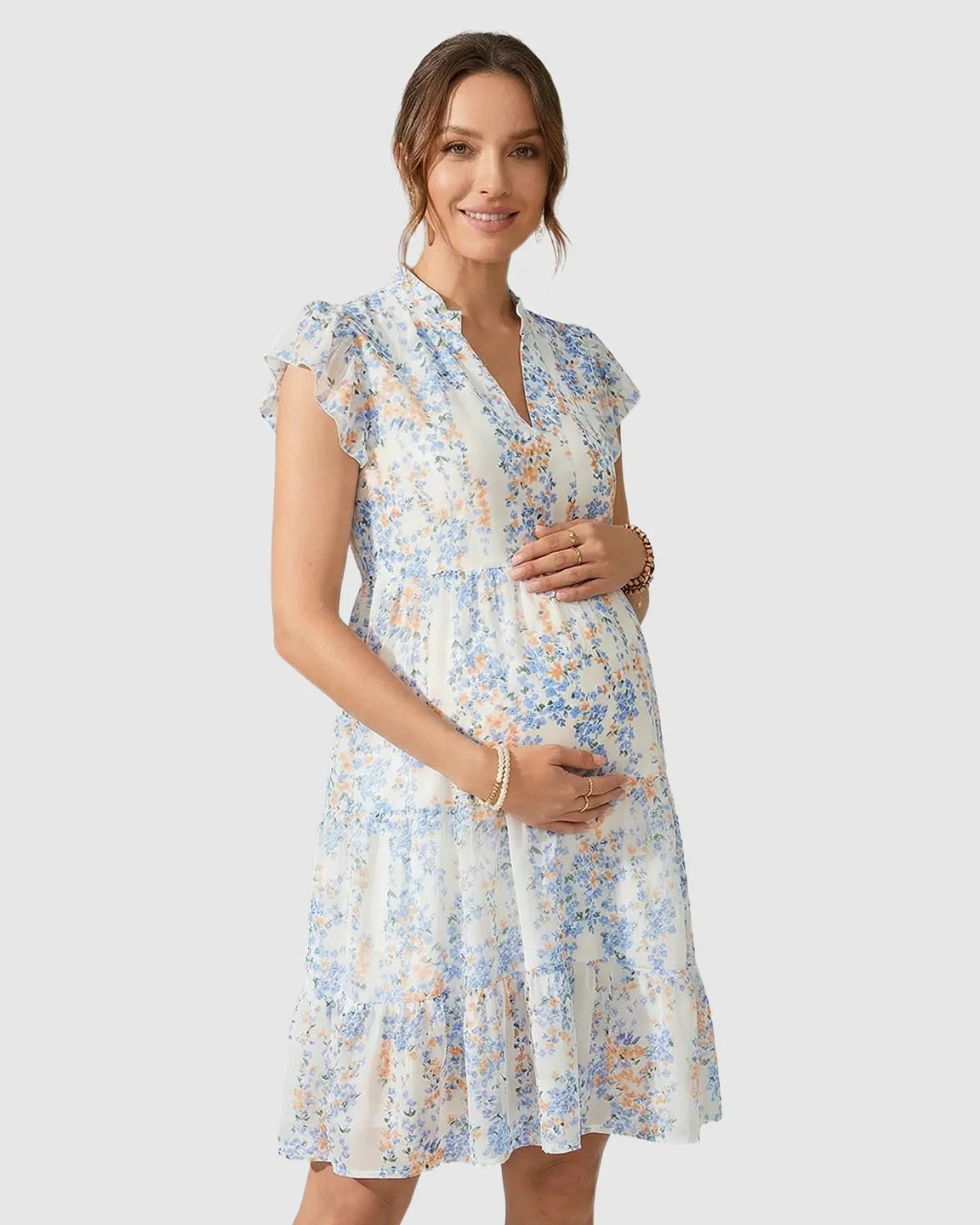 White chiffon A-line maternity dress with blue and orange floral print, flutter sleeves, and a tiered skirt.