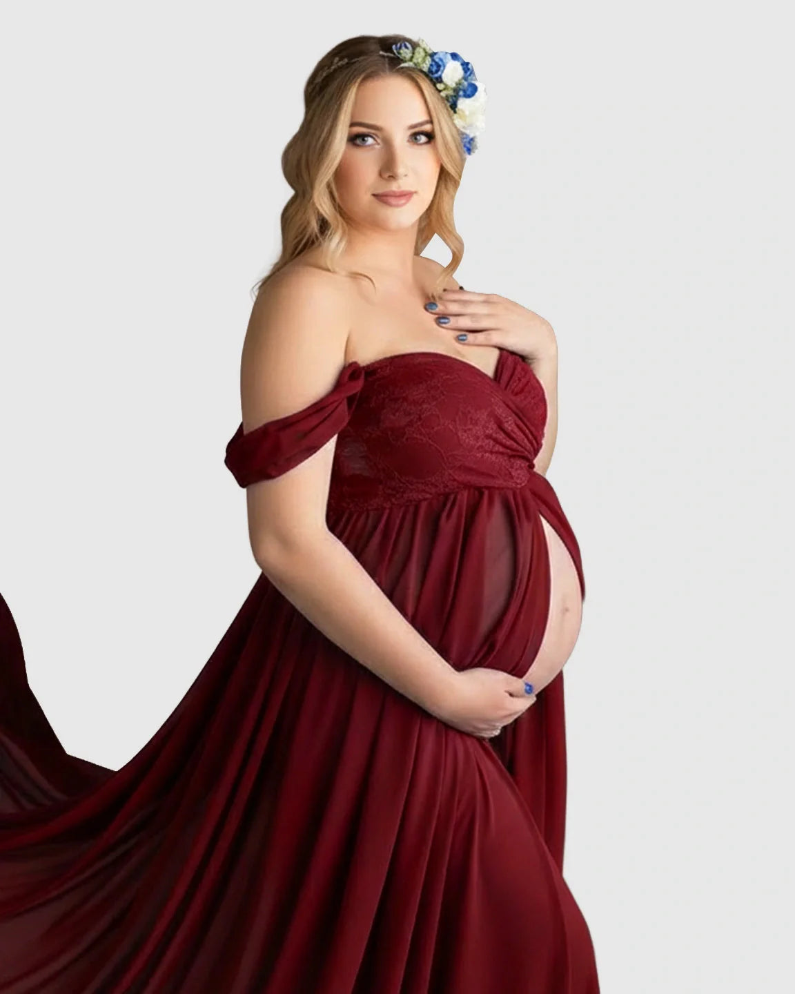 Pregnant woman in a flowing, off-shoulder burgundy chiffon maternity gown with a long train, holding her belly.