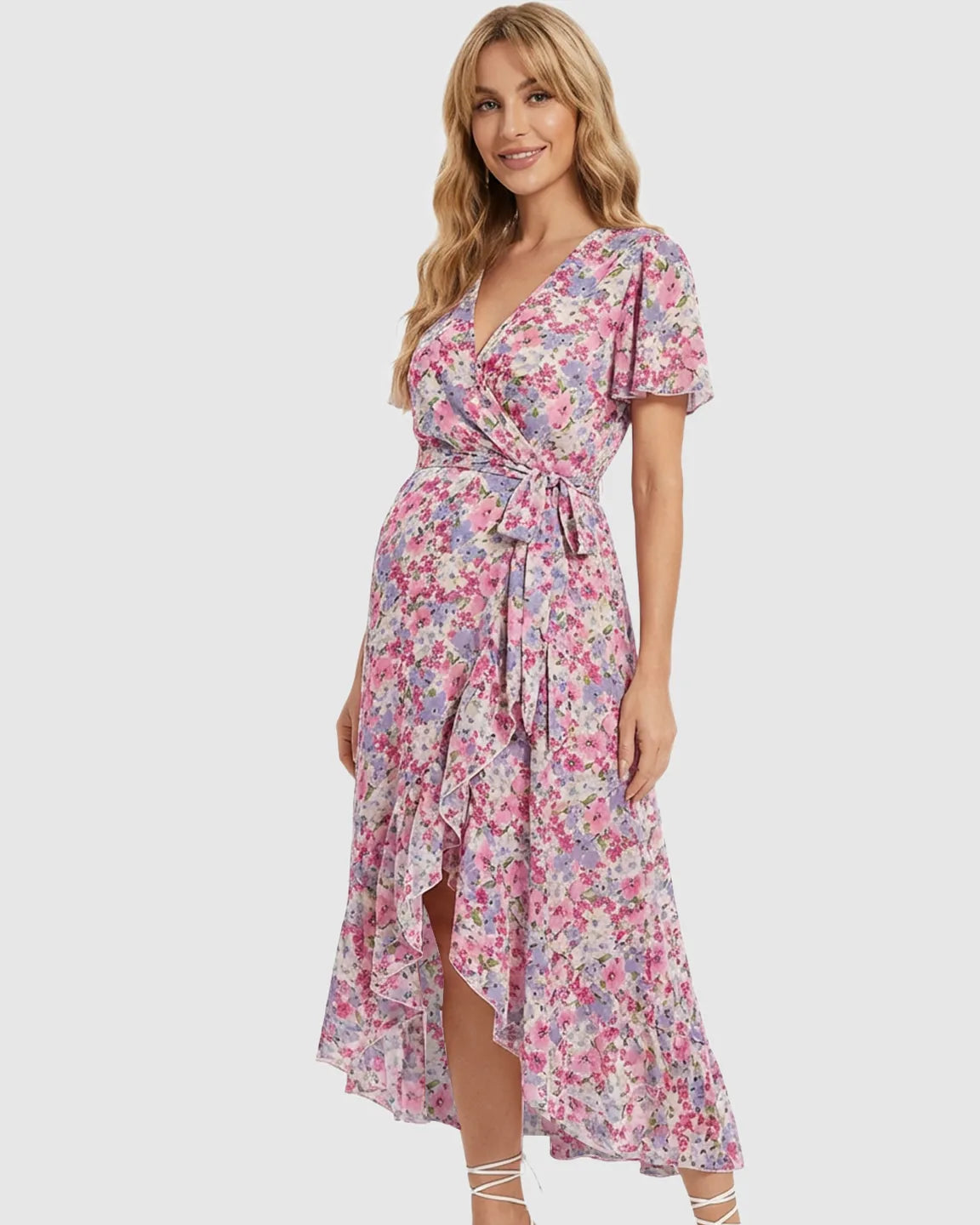 Blonde model wearing a pink and purple floral V-neck maternity midi dress with a ruffled hem and tie waist.