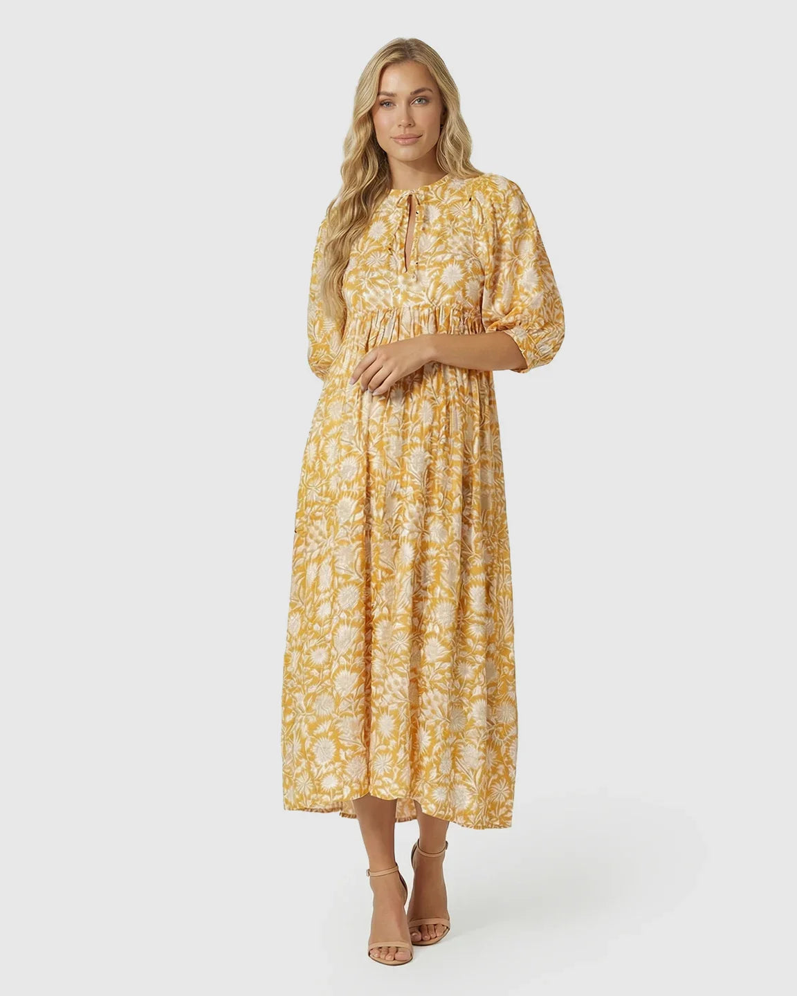 Woman in a yellow floral loose-fit maternity midi dress with gathered shoulders, puff sleeves, and knot detail.