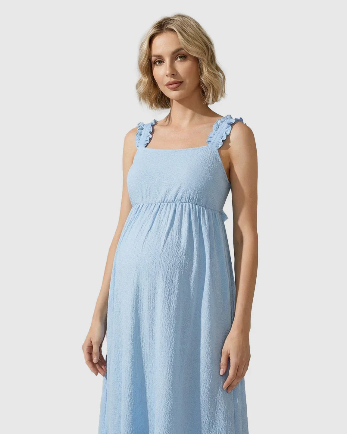 Pregnant woman in a light blue ruffled strap maternity maxi dress with a square neckline and empire waist.