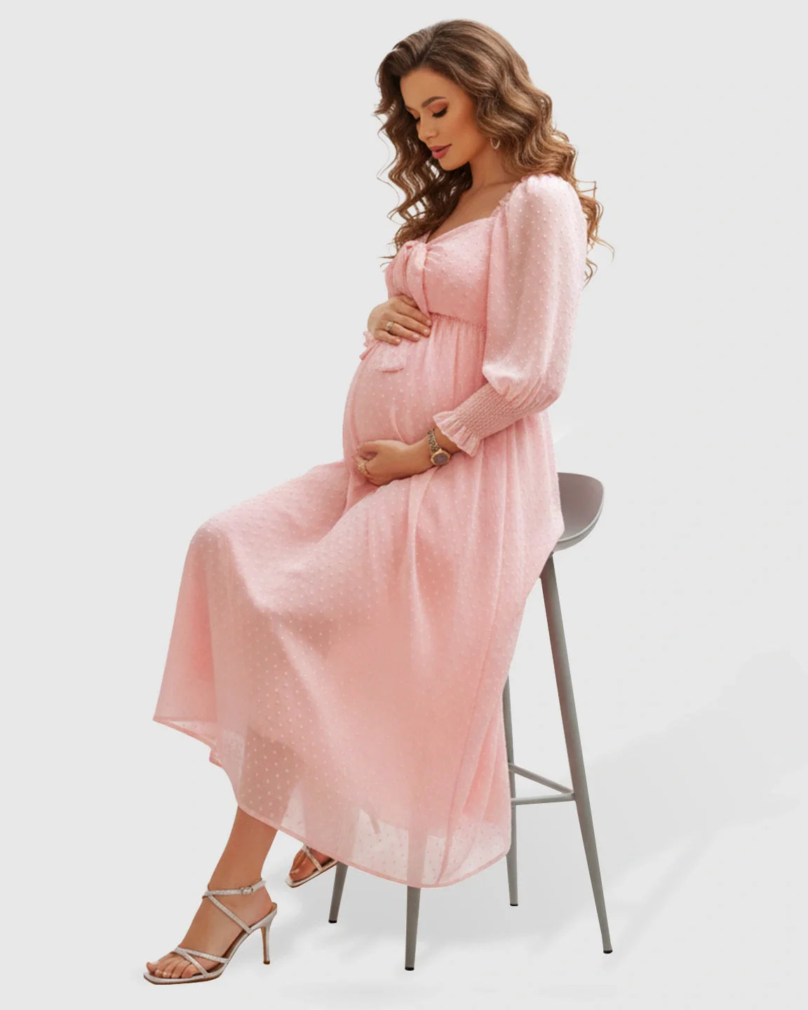 Pregnant woman in a pink polka-dot chiffon maternity maxi dress with a square neckline and long sleeves.