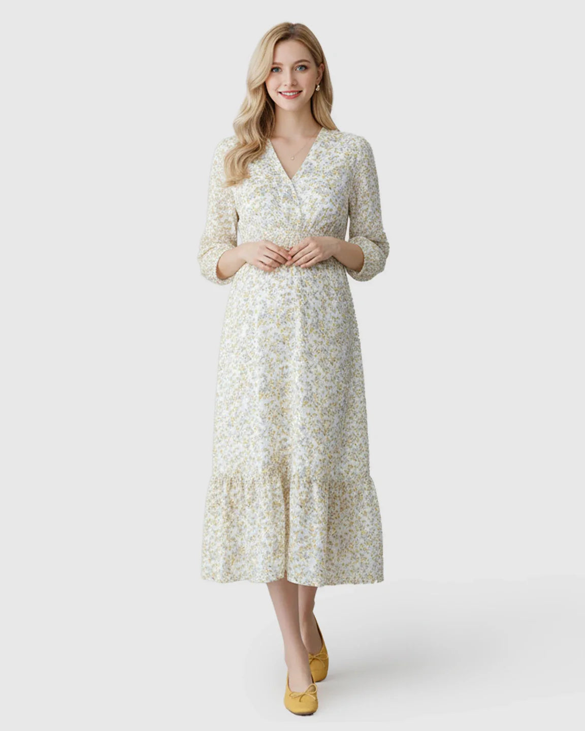 Blonde woman in a white floral ruffle hem smocked waist maternity midi dress with yellow flowers.