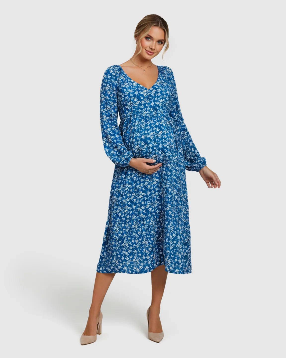 Smiling pregnant woman in a blue floral chiffon A-line maternity dress with long balloon sleeves.