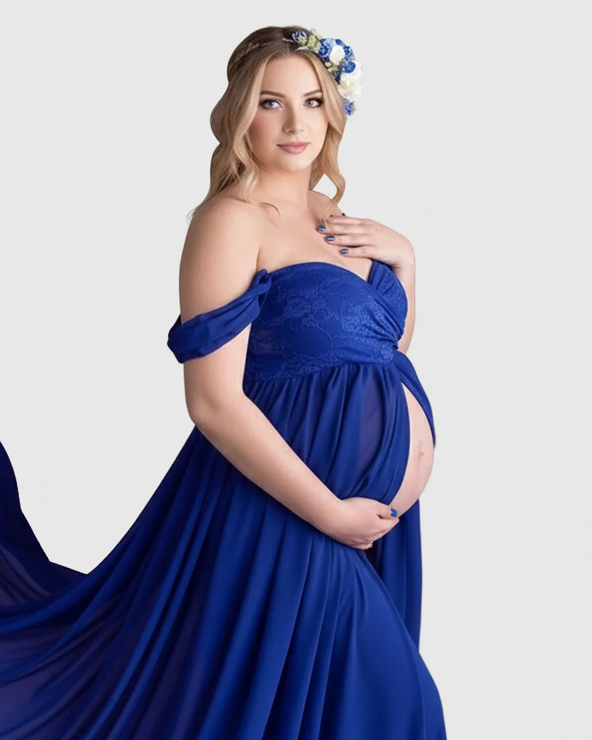 Blonde pregnant woman in a royal blue off-shoulder chiffon maternity gown with a long train and floral headband.