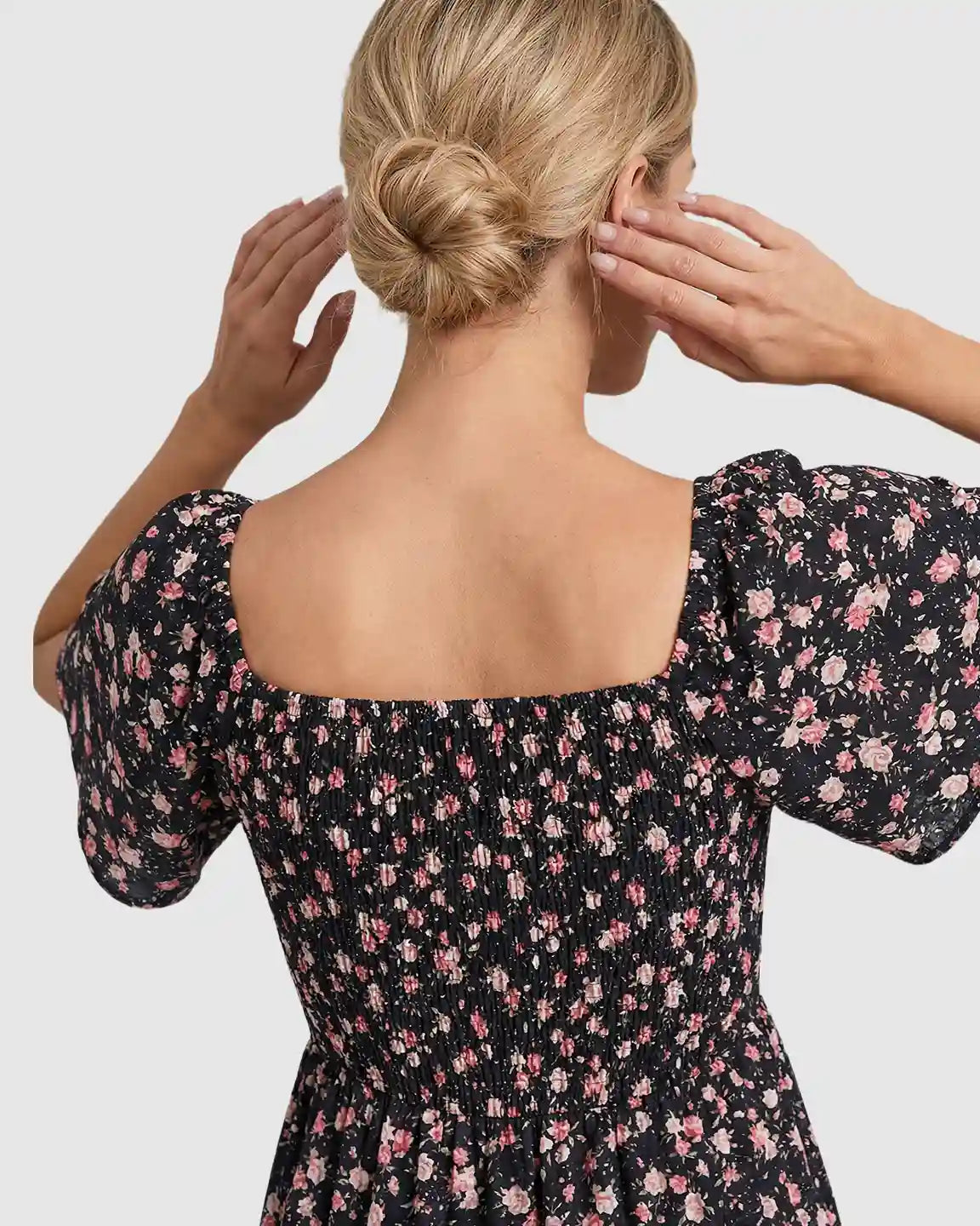 Black maternity midi dress with pink floral print, smocked back, and flutter sleeves.
