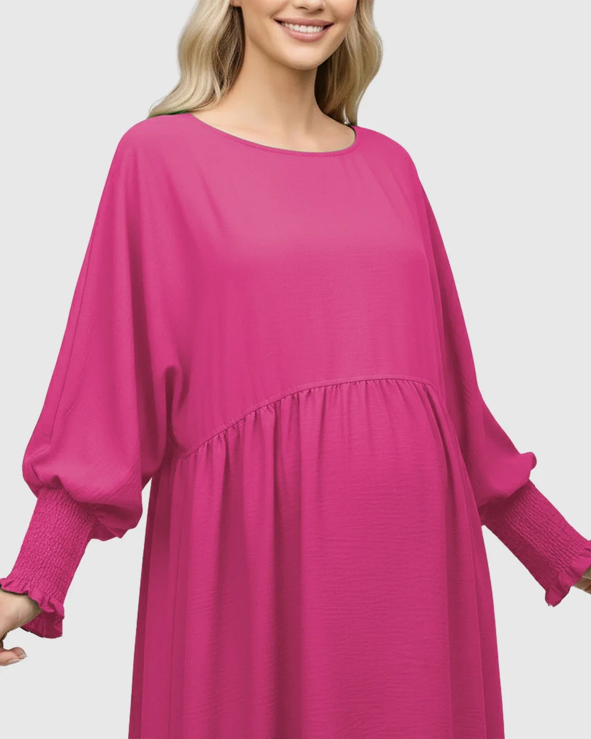 Smiling pregnant woman in a fuchsia smocked sleeve casual dress with a round neckline.