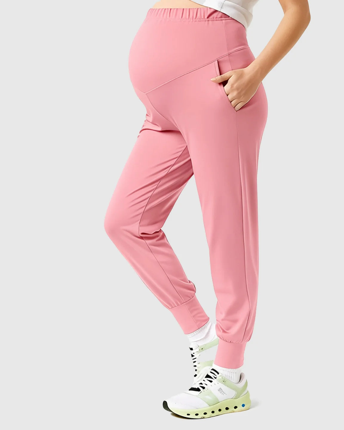 Pink supportive slim-fitting maternity joggers with a high-waist design and side pockets, worn by a pregnant woman.